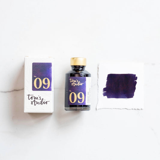 Fountain pen ink bottle with gold cap, No. 09 label, and purple ink swatch