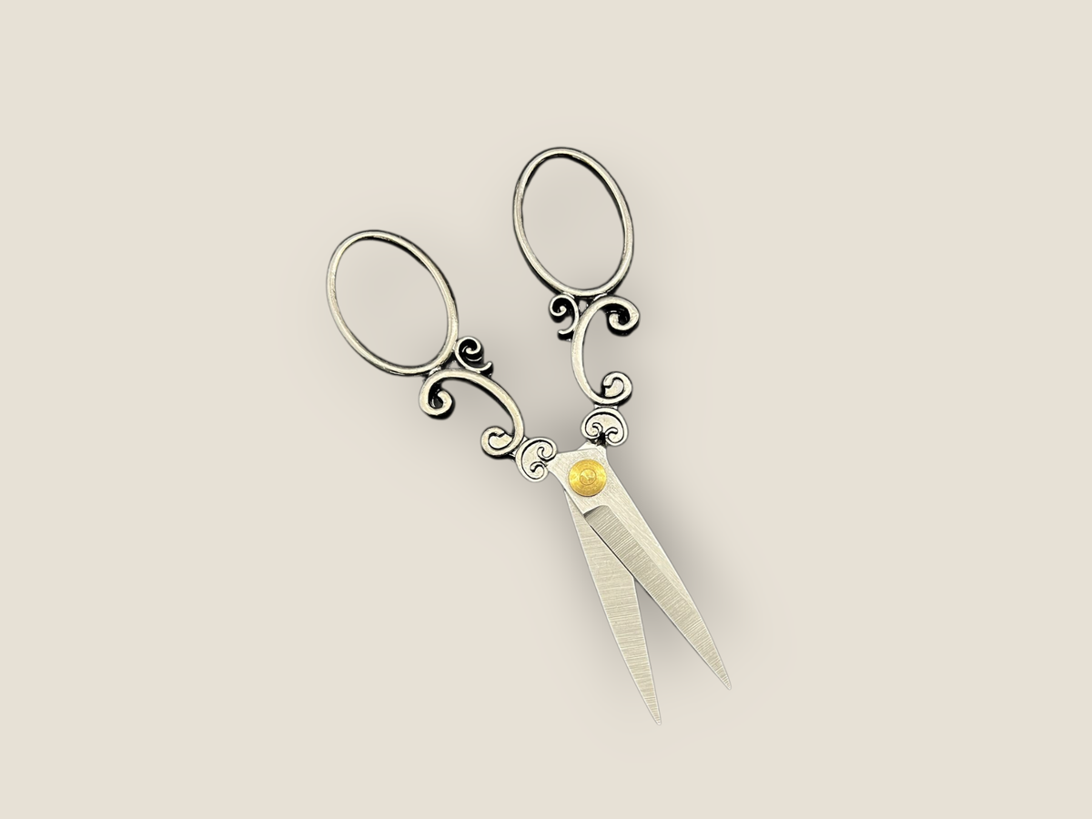 Arabesque scissors with ornate scroll handles, three oval loops, and gold jewel accents