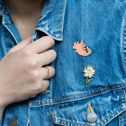 Pink axolotl enamel pin on blue denim jacket, gold-edged curled tail charm