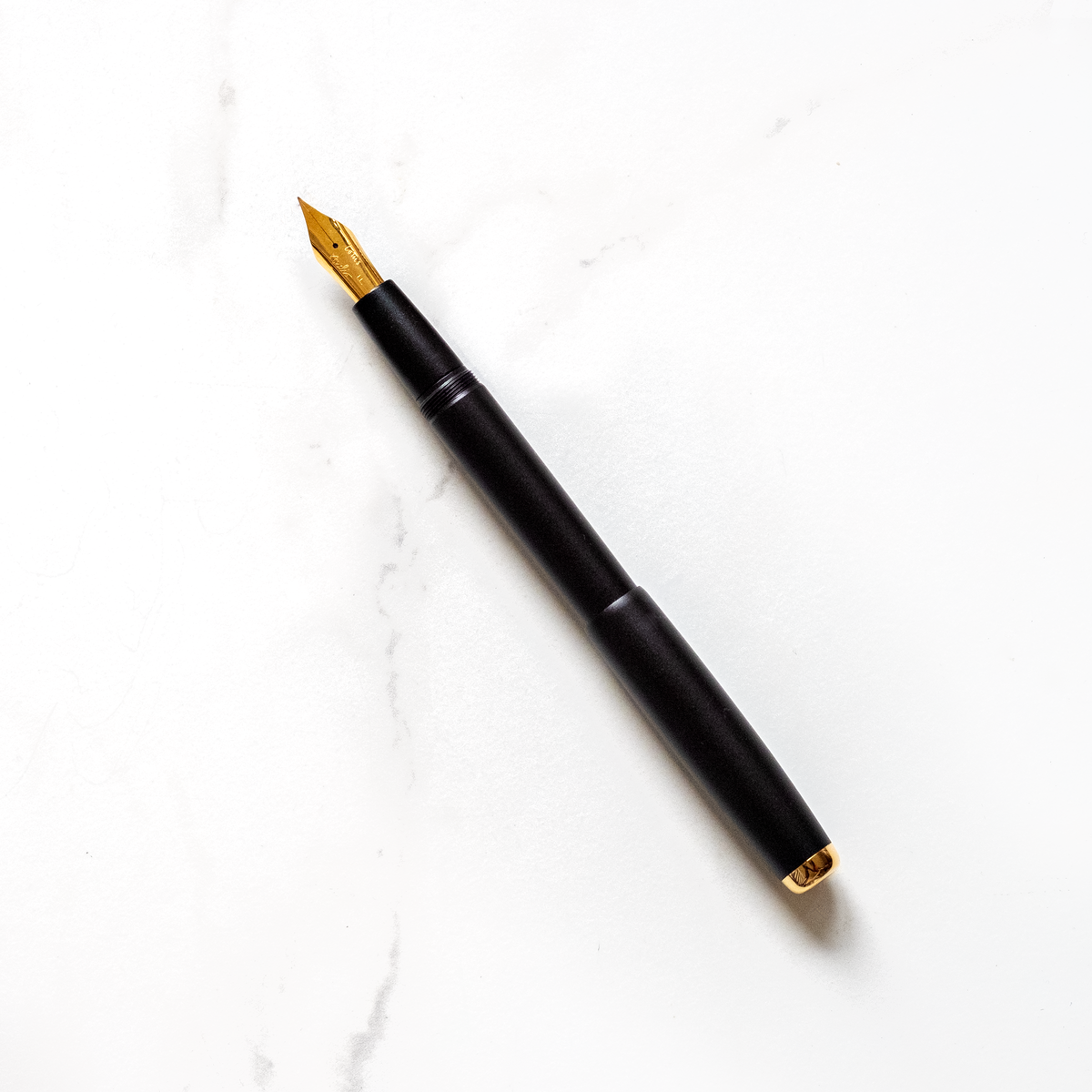 Black fountain pen with gold nib, shown at an angle