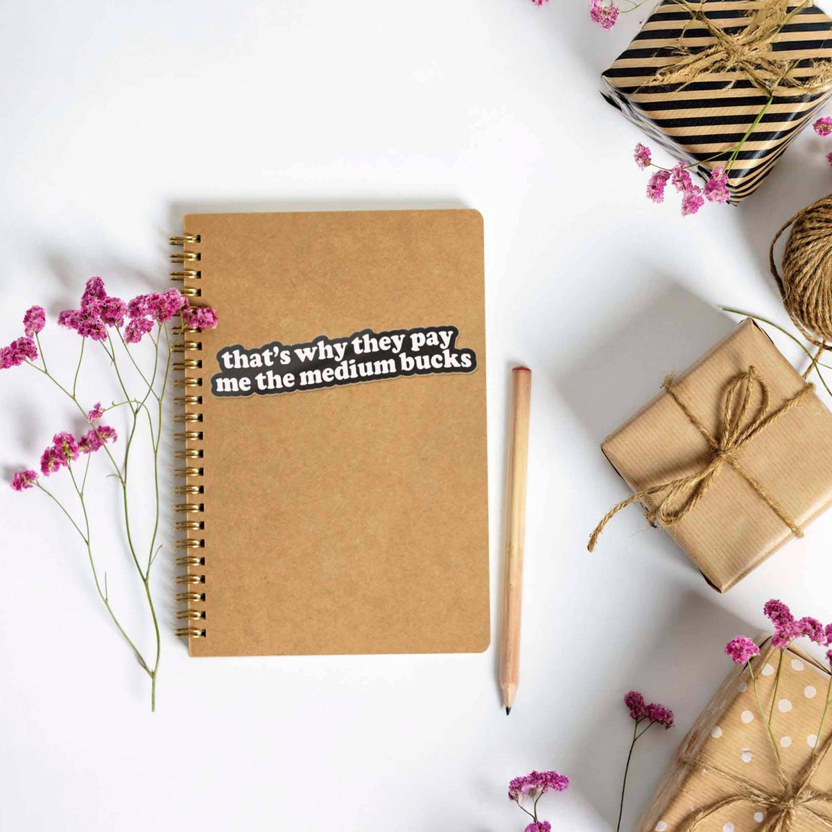 Funny quote sticker on kraft notebook: 'that's why they pay me the medium bucks'