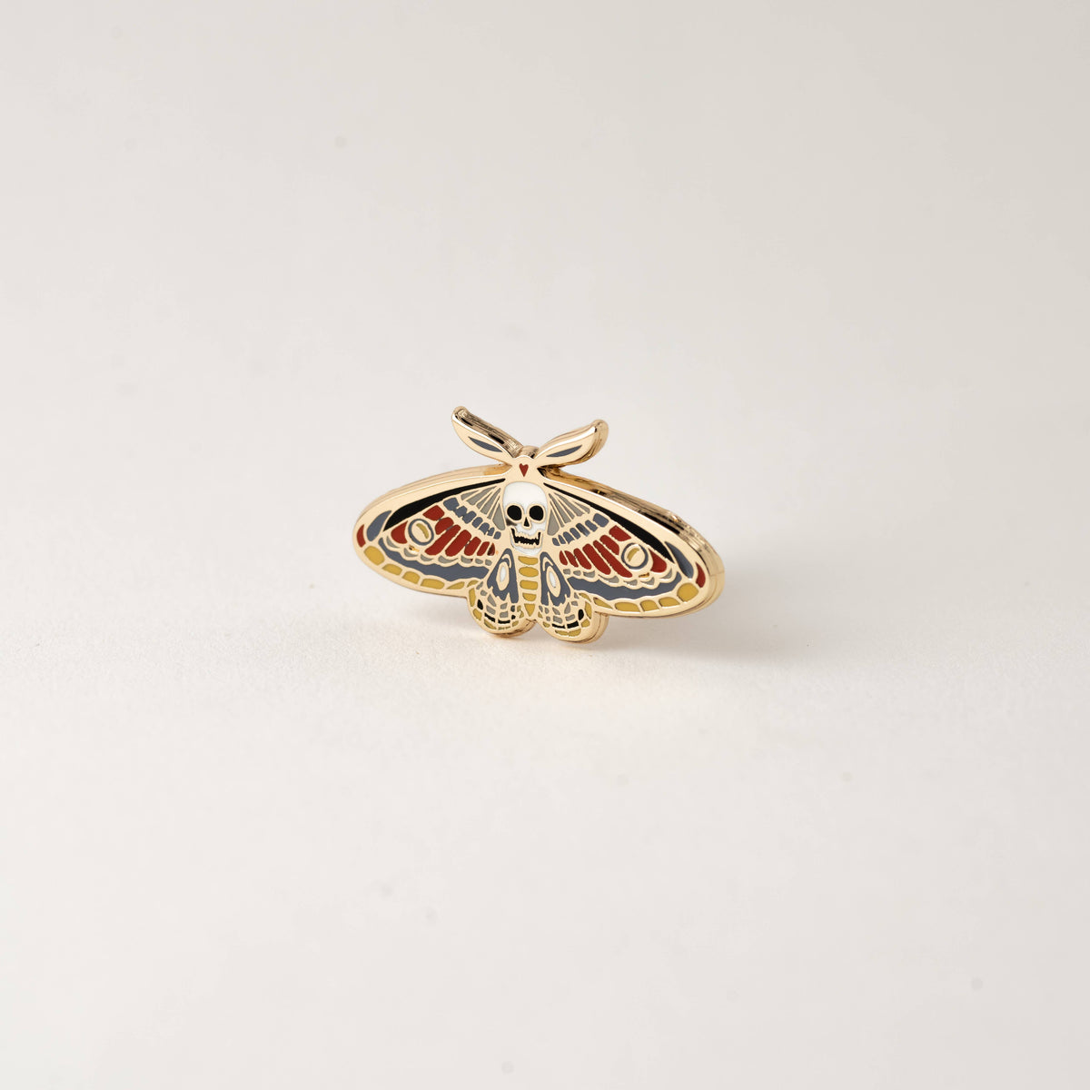 Enamel death moth skull pin with spread wings and gold-tone outline