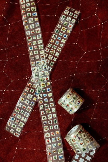 Transparent tape with mini postage stamps, two crossed strips with rolls beside them