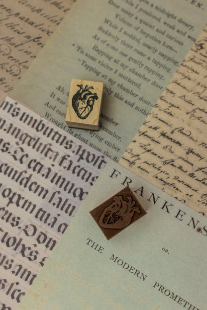 Two wooden stamp blocks with carved crest designs on vintage-style paper