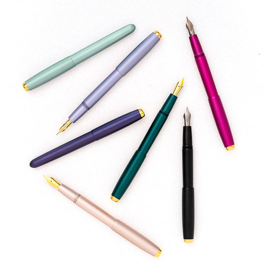 Assorted fountain pens in green, lilac, purple, teal, black, and pink.