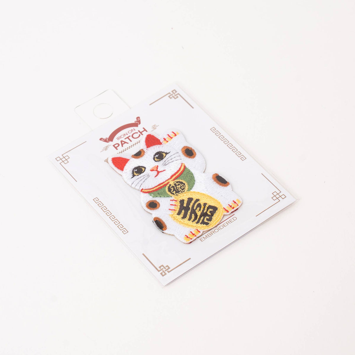 Lucky cat iron-on patch on card, white cat with red hat and gold coin emblem
