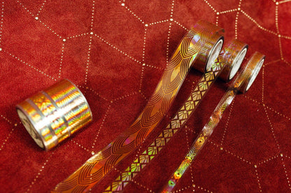 Gold patterned transparent tape rolls and ribbons, with one roll shown left