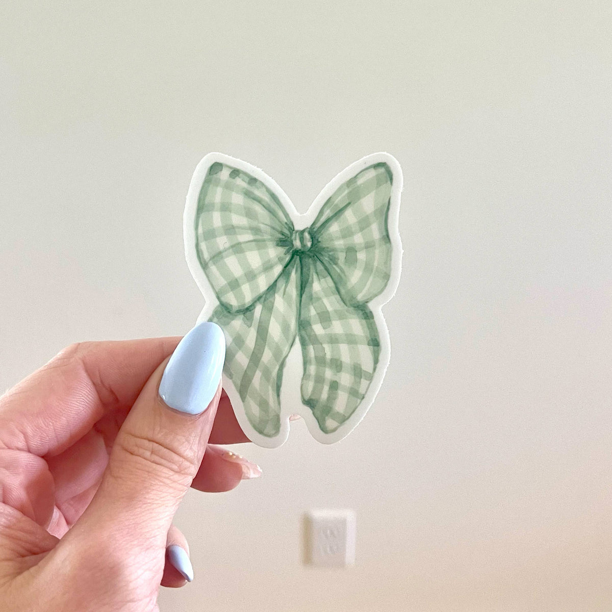 Green gingham bow vinyl sticker with white border, ribbon-knot center