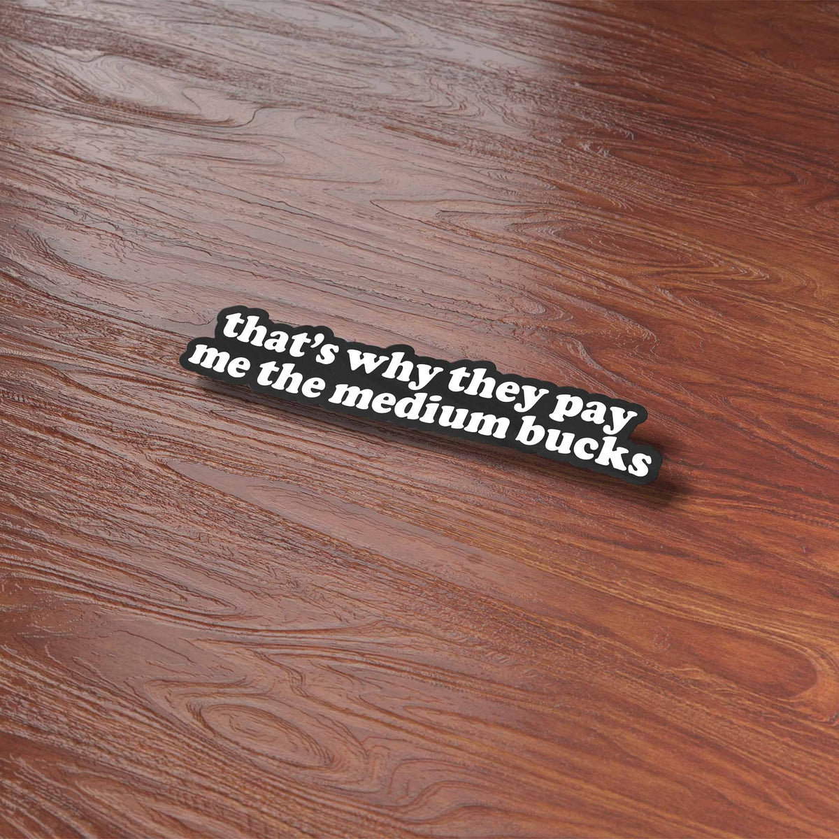 Funny quote sticker on wood surface: 'that's why they pay me the medium bucks'