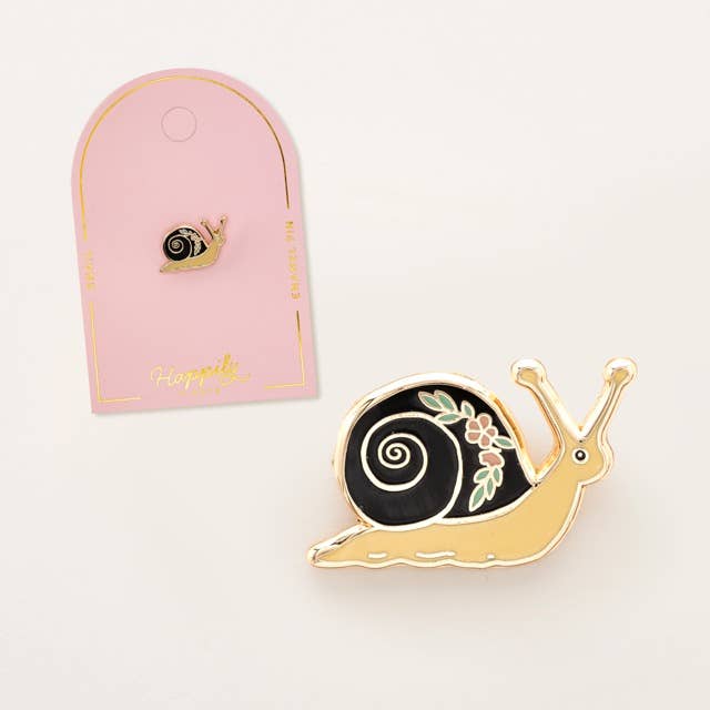Garden snail enamel pin with black swirl shell and gold-tone body, on card