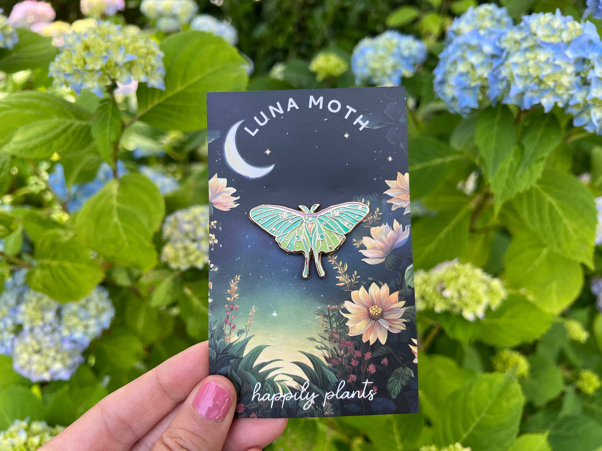 Luna moth pin product card in hand outdoors, with illustrated moth and Happy plants text