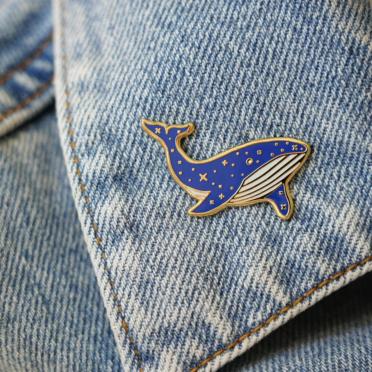 Blue whale enamel pin on denim jacket pocket