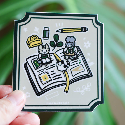 Vinyl sticker of open book illustration with bunny, cat, and clover icons