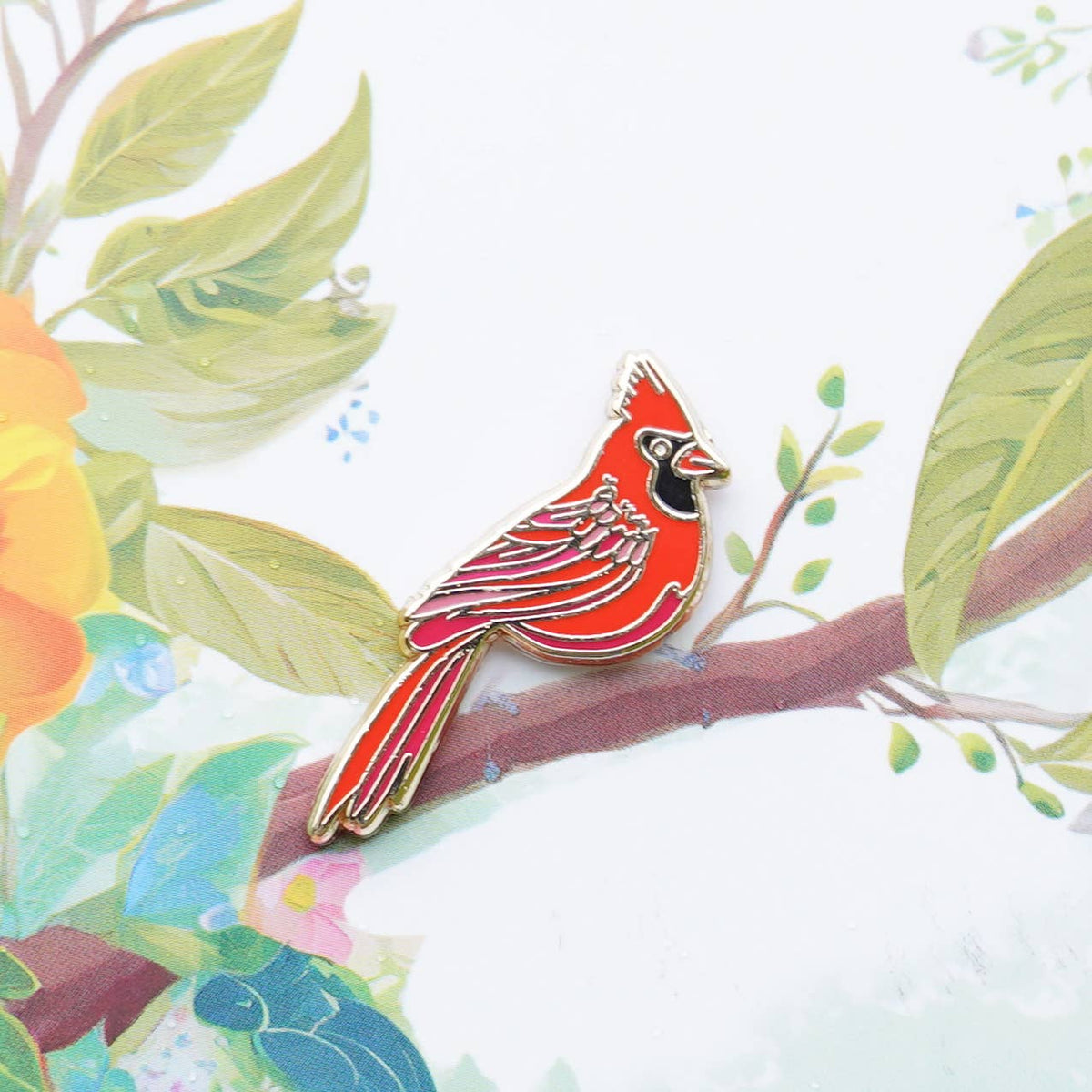 Red cardinal enamel pin on a printed fabric background