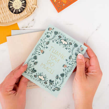 Thank you card with gold foil lettering and floral border, shown without its envelope