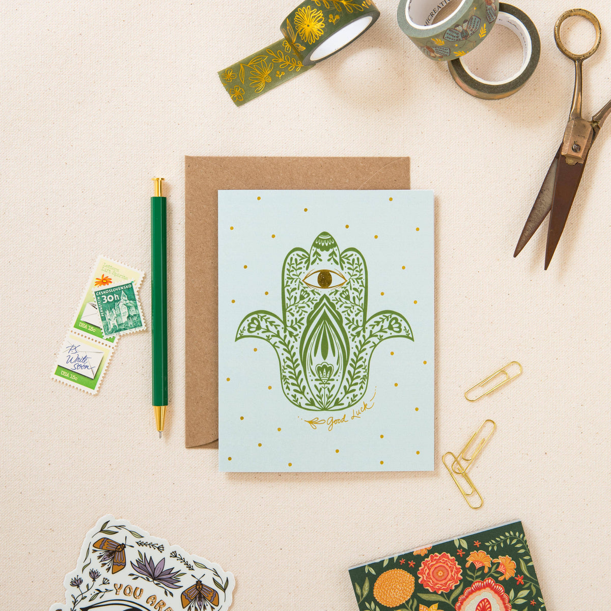 Hamsa protection greeting card with green artwork, gold foil accents, and kraft envelope