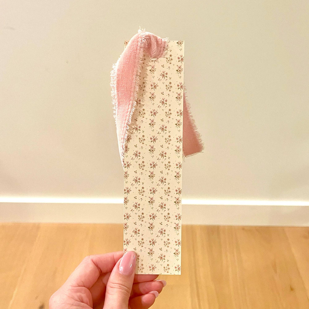 Ditsy floral bookmark with pink velvet ribbon loop, held in hand