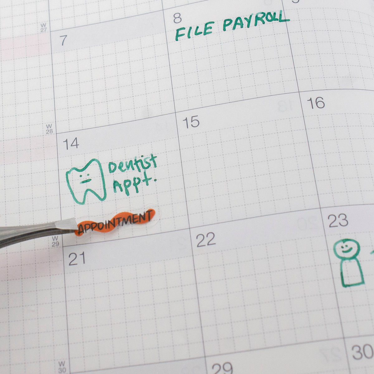 Close-up of applied calendar stickers: dentist appointment label on grid paper