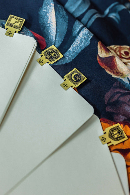 Blank notebook pages with small gold square page markers and circular emblem