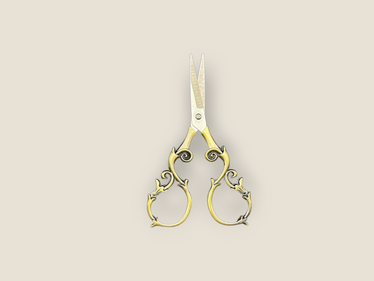 Ornate gold-toned scissors with curled filigree handles and narrow blades