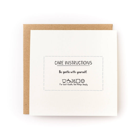 Letterpress care instructions card with centered text and dashed border, on kraft envelope