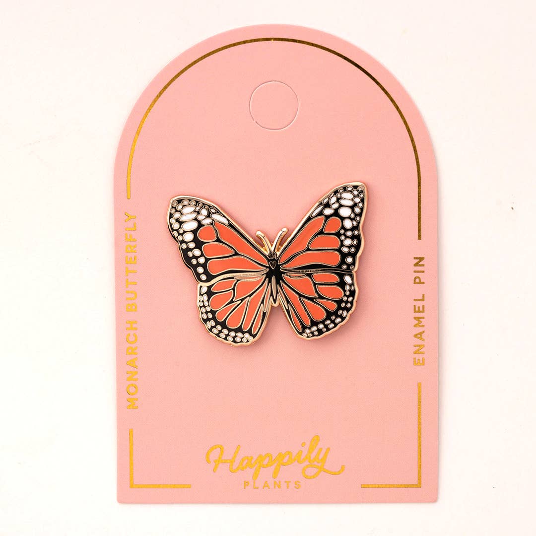 Monarch butterfly pin on a pink backing card with gold-tone details.