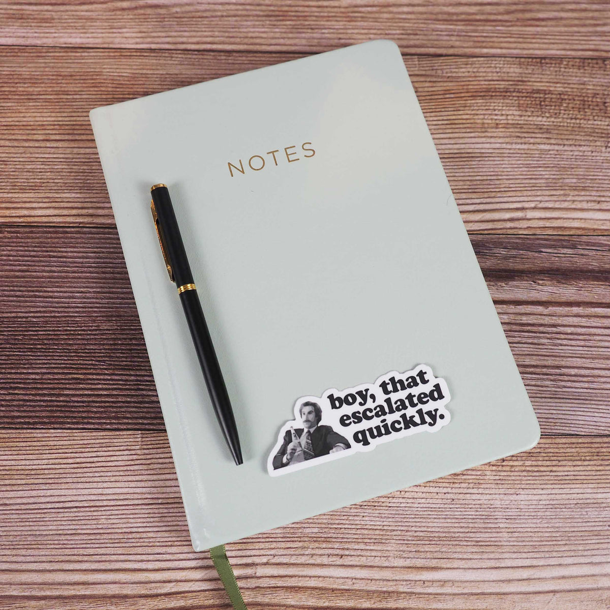 Boy escalated quickly quote sticker on white notebook with pen