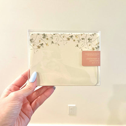 Cream botanical floral stationery envelope in a clear sleeve, held by hand