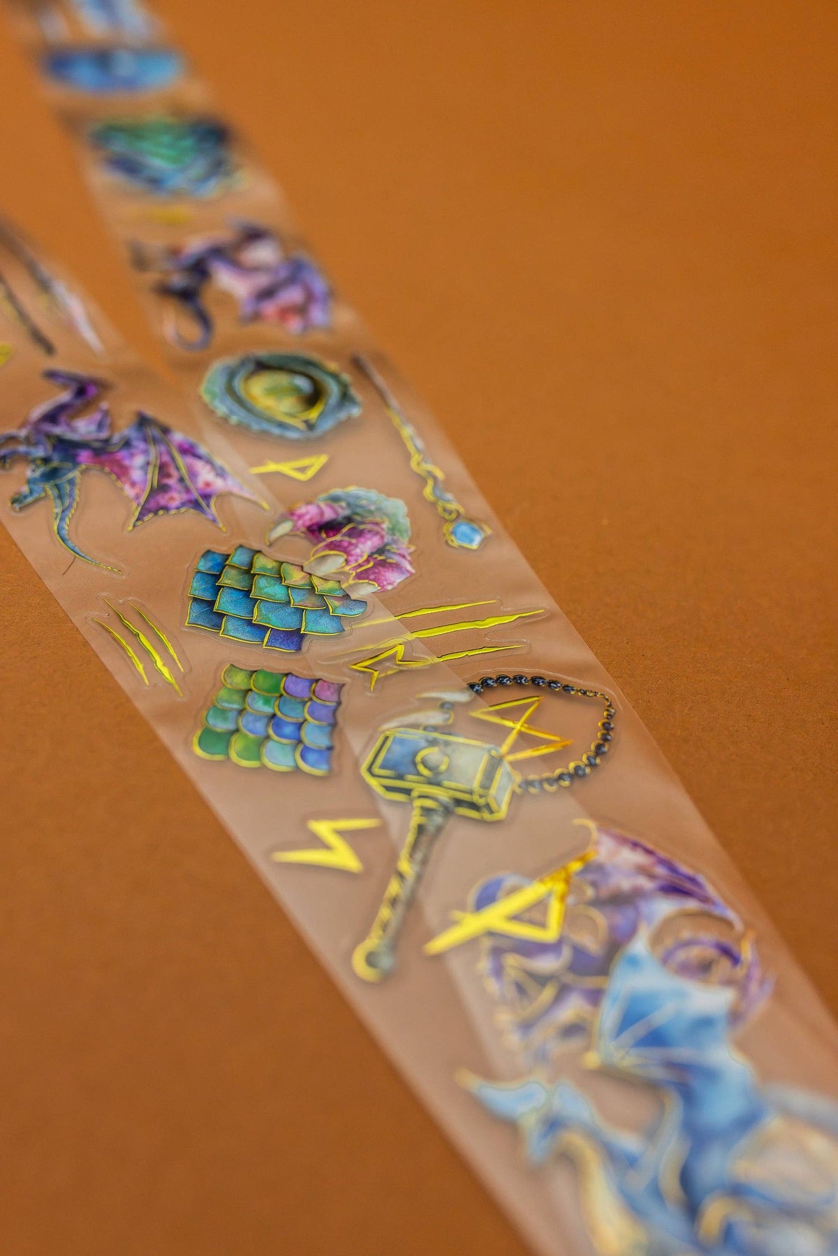 Transparent tape strip with holographic dragon eye, scales, and rune symbols