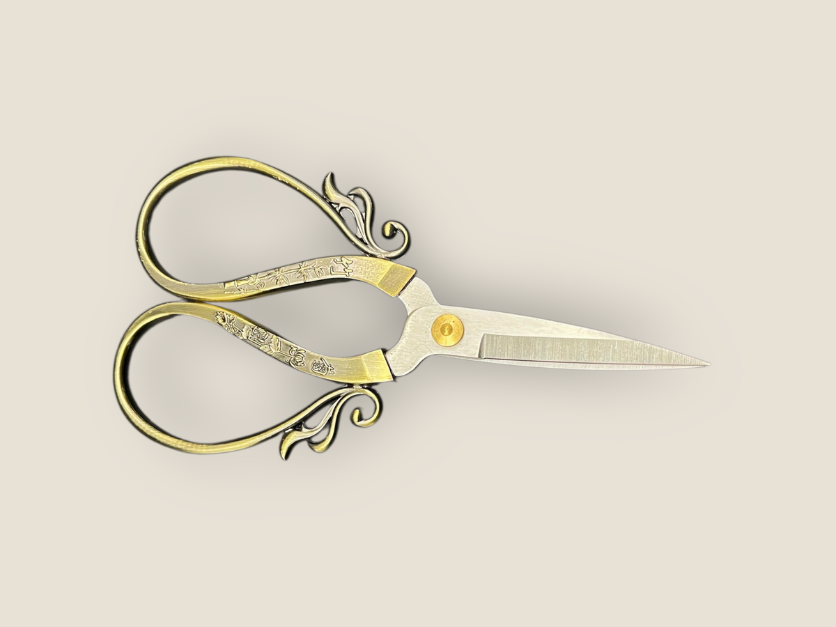 Large cutting scissors, side view with gold handles and long pointed blades